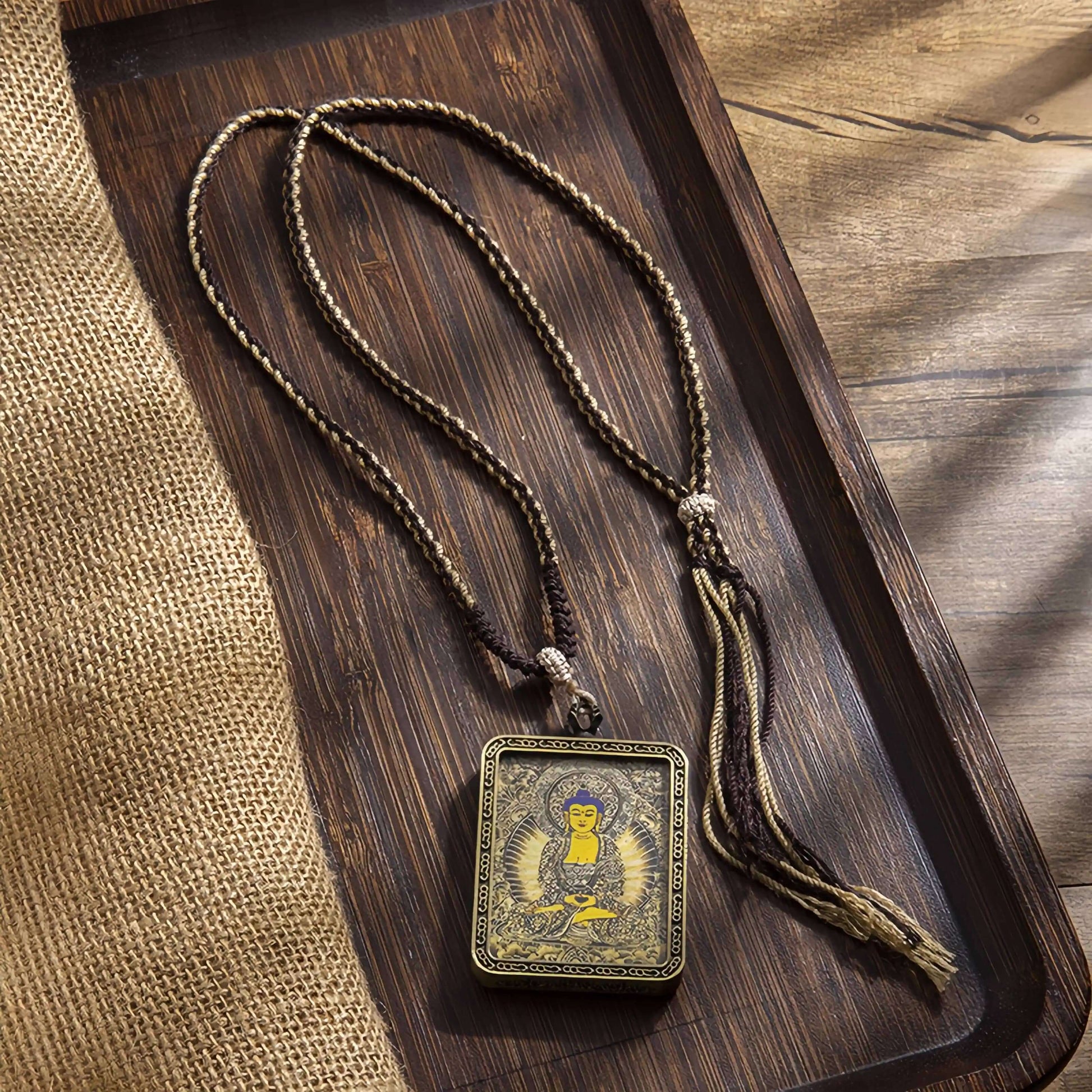 Tibetan Thangka Eight Protector Deities Pendant on a wooden tray with braided cord and tassel.