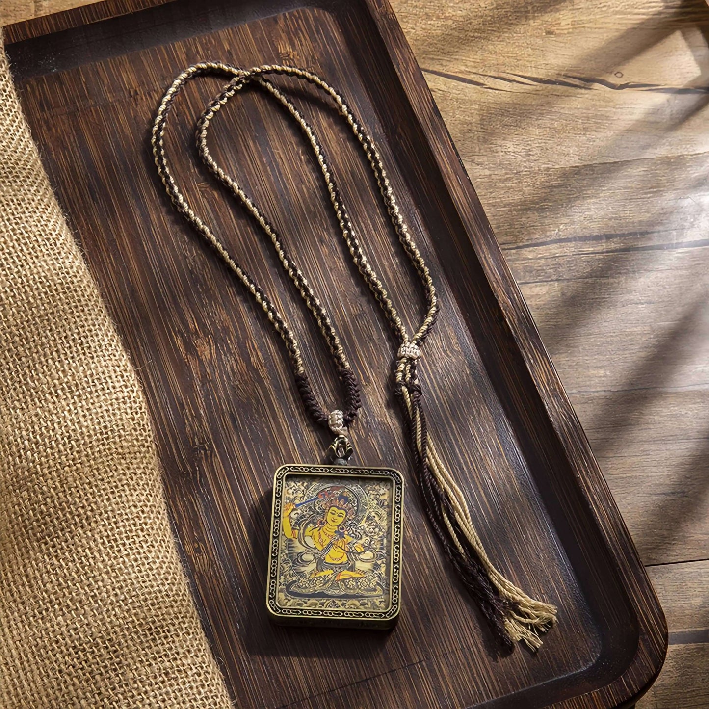 Tibetan Thangka Eight Protector Deities Pendant on a wooden tray with a textured background.