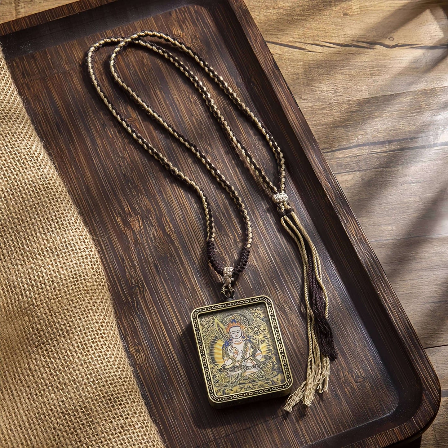 Tibetan Thangka Eight Protector Deities Pendant with braided cord on wooden tray